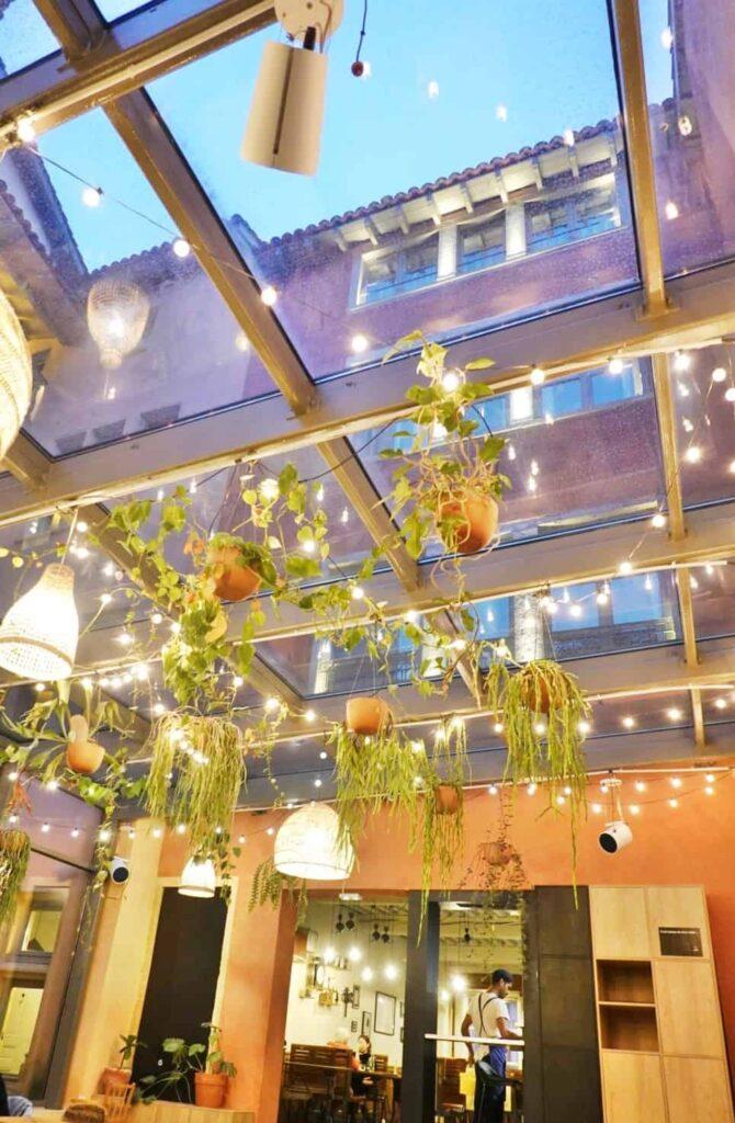 Indoor seating at Food Traboule Restaurant in Lyon with beautiful tour rose in the background and lights and plants